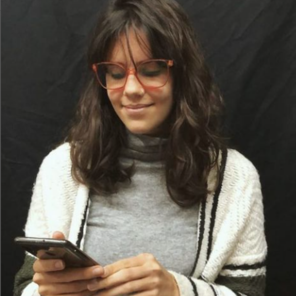 This is a photo of a woman looking down at her phone in front of a black background.