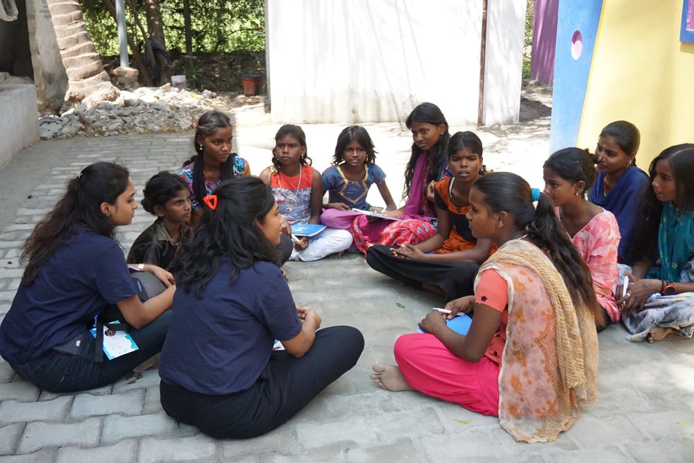 A photo of Dhivya Krishna and another WTM Chennai volunteer talking with girls in Chennai about technology as part of International Women’s Day 2022.