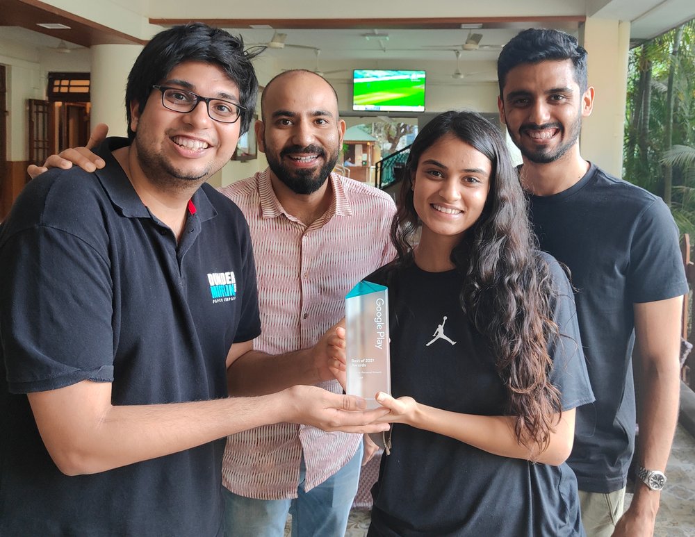 Four people smiling at the camera and holding a trophy