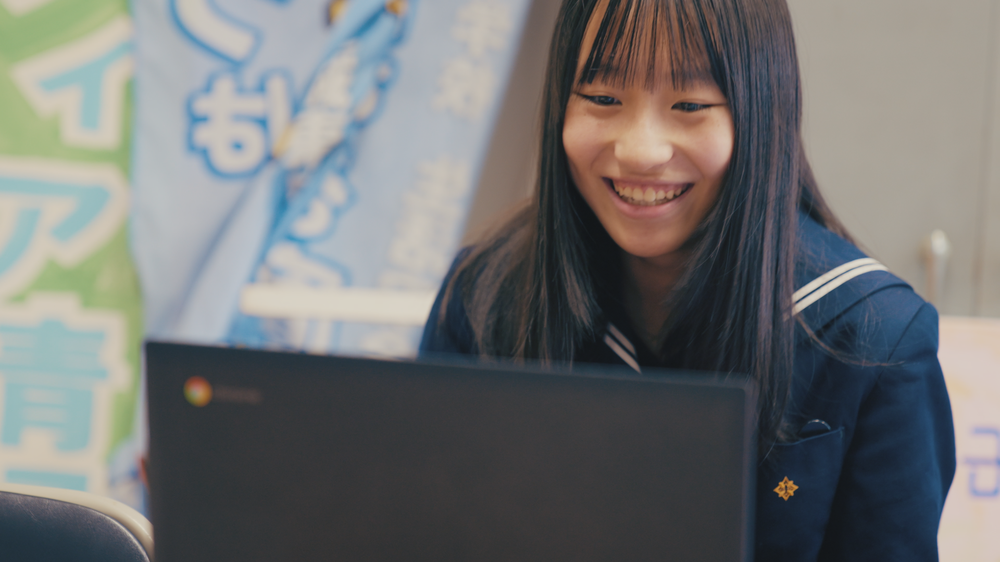 Photo of student smiling and looking at a Chromebook screen