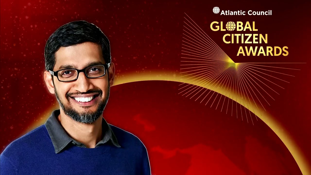 A video of Sundar Pichai delivering his acceptance remarks at the Atlantic Council global citizen awards. He is wearing a black tuxedo, standing at a lectern on a stage with a red backdrop.